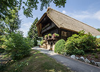 alter Bauernhof mit Strohdach und Blumenschmuck